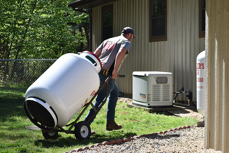 Employee rolling a propane tank to a business