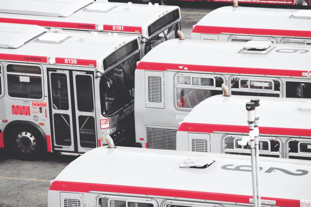 A fleet of red and white public buses resting in a parking lot